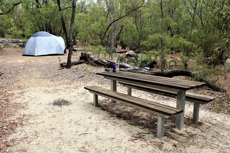 A tent and picnic table in a forest in Australia.