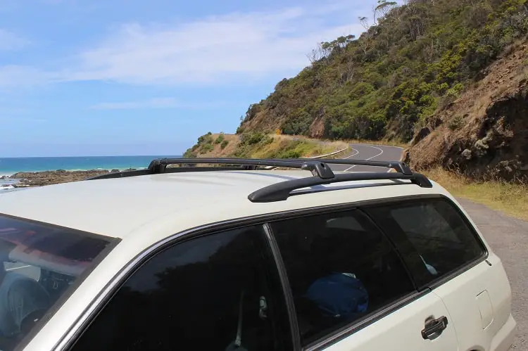 A car parked on the Great Ocean Road with the ocean in the background.