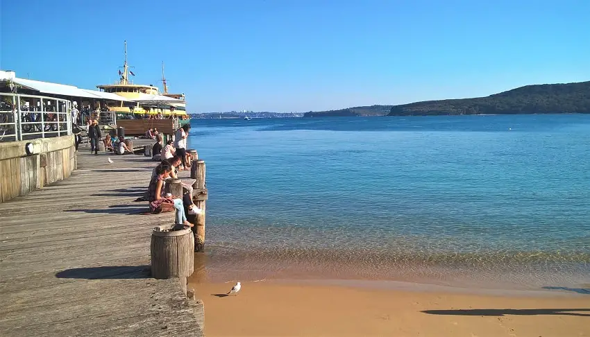 People waiting at Manly Wharf for the ferry back to the city on a beautiful sunny day. The water is crystal clear.