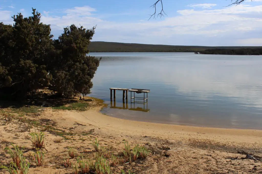 Glassy lake and beach at Millers Point Reserve, a free camping ground, WA.