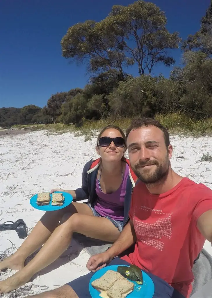 Blogger Lisa Bull eating a picnic with a travel mate on a beach in Albany WA.