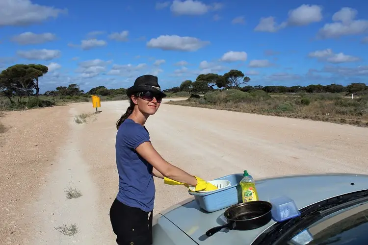 Travel blogger Lisa Bull washing up on the road whilst crossing the Nullarbor Plain, Australia.