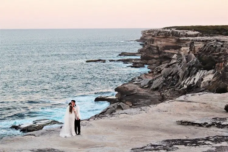 A couple kissing on their wedding day on the cliffs at sunset at Cape Solander.