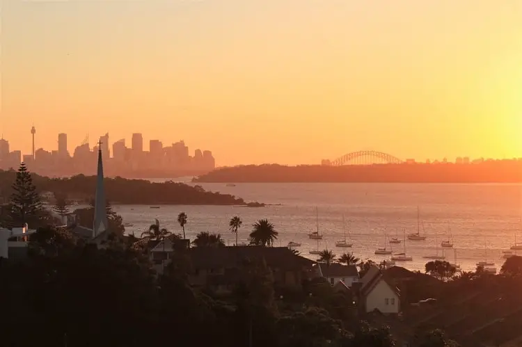 Bright orange sunset behind the Sydney skyline viewed across the water in Watsons Bay.