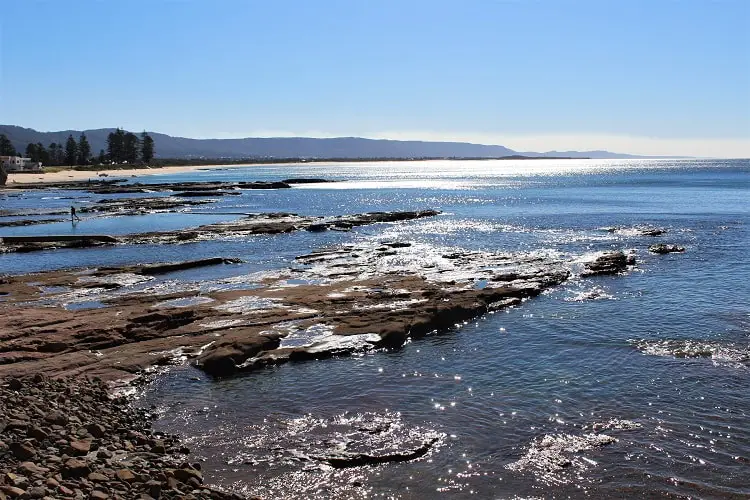 Stunniing rocky coastling in Wollongong, Australia with sun on the ocean.