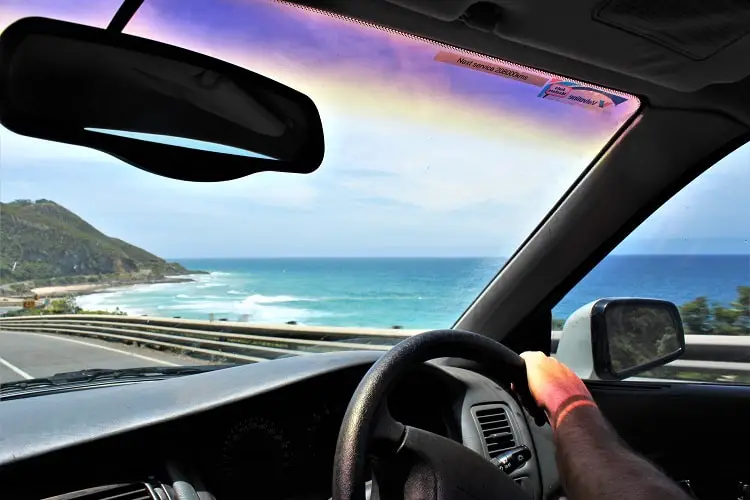 Backpacker driving along the Great Ocean Road in Australia, overlooking the ocean.