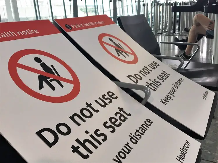 Signs on seats at Heathrow Airport ensuring passengers social distance and don't sit close together.