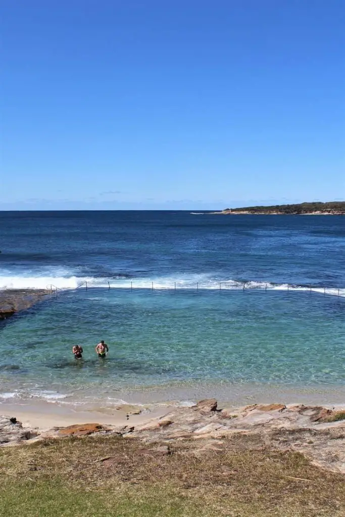 Men swimming in crystal clear water at an ocean pool in Cronulla, Sydney.