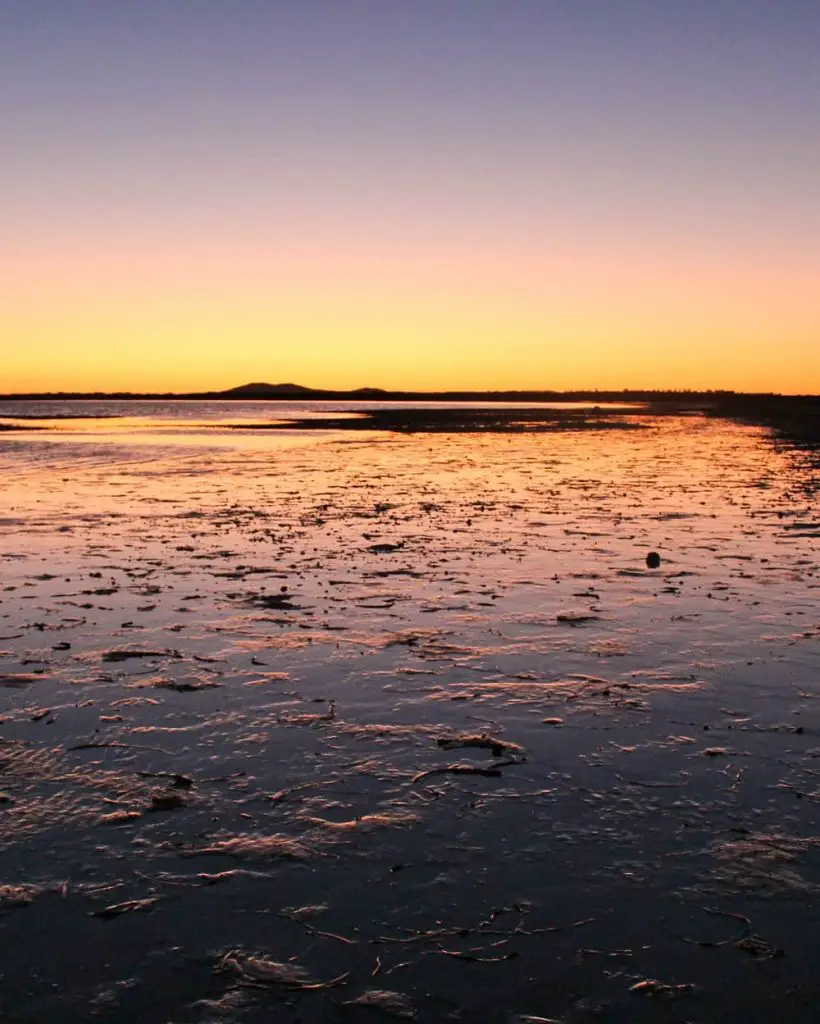 Gorgeous orange and purple sunset reflecting on wet sand in Whyalla SA.