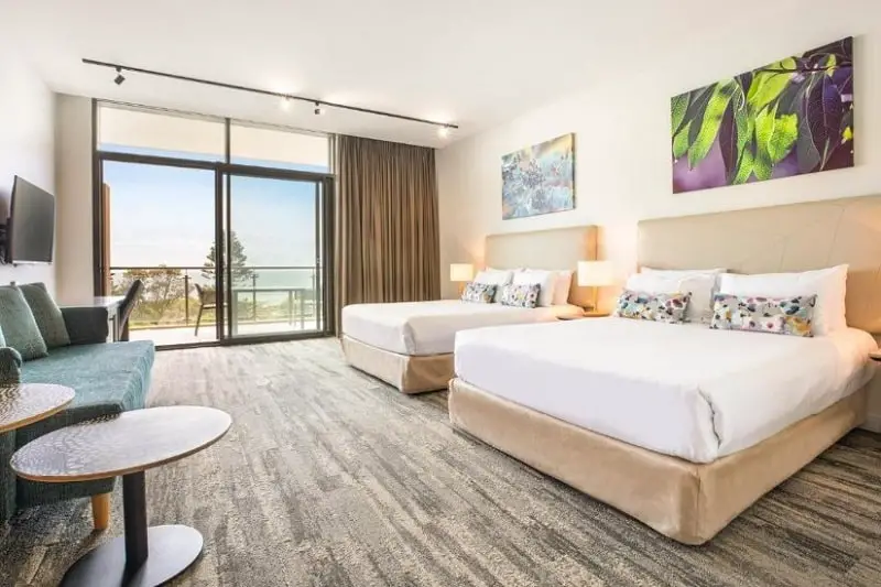 Two double beds and a balcony with ocean view at Narrabeen Sands Hotel in Sydney's Northern Beaches.