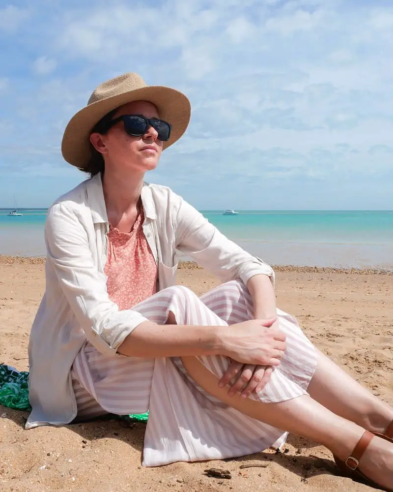 Travel blogger Lisa Bull sitting on the sand at Cullen Beach in Darwin, Australia.