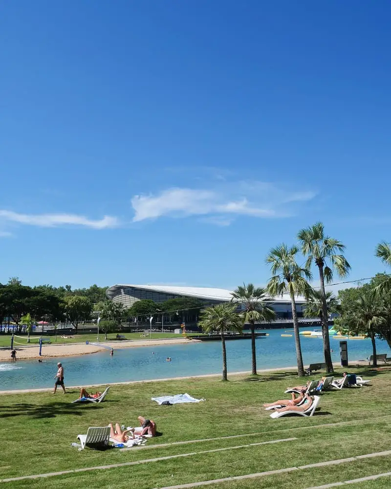 Sunbathers on the grass next to Darwin's city lagoon and manmade beach.