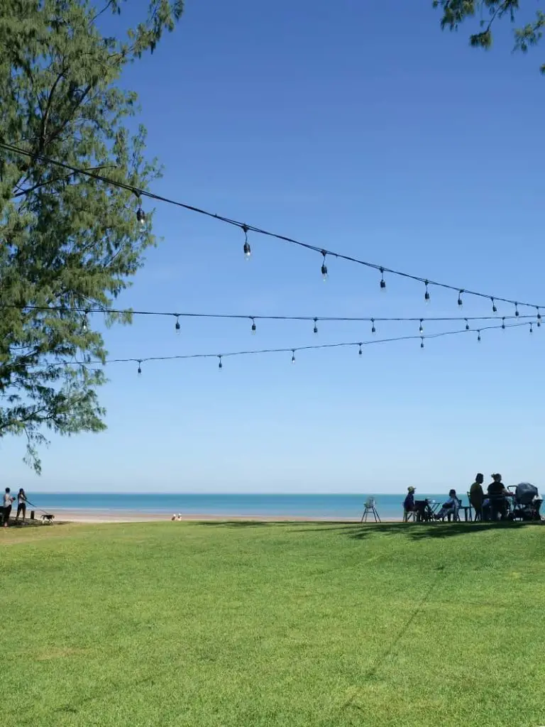 String of lights and patrons sitting outside overlooking Casuarina Beach at De La Plage Cafe.