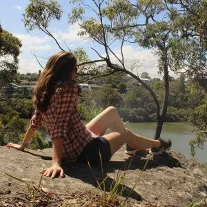 Lisa Bull from Dreaming of Down Under travel blog sitting on a rock overlooking a river in Sydney.