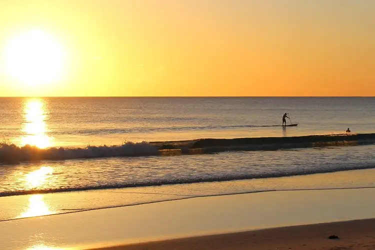 Someone stand-up paddle boarding at sunset at Scarborough Beach in Perth, Australia.