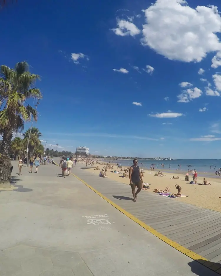 People walking along the promenade at St Kilda beach in Melbourne.